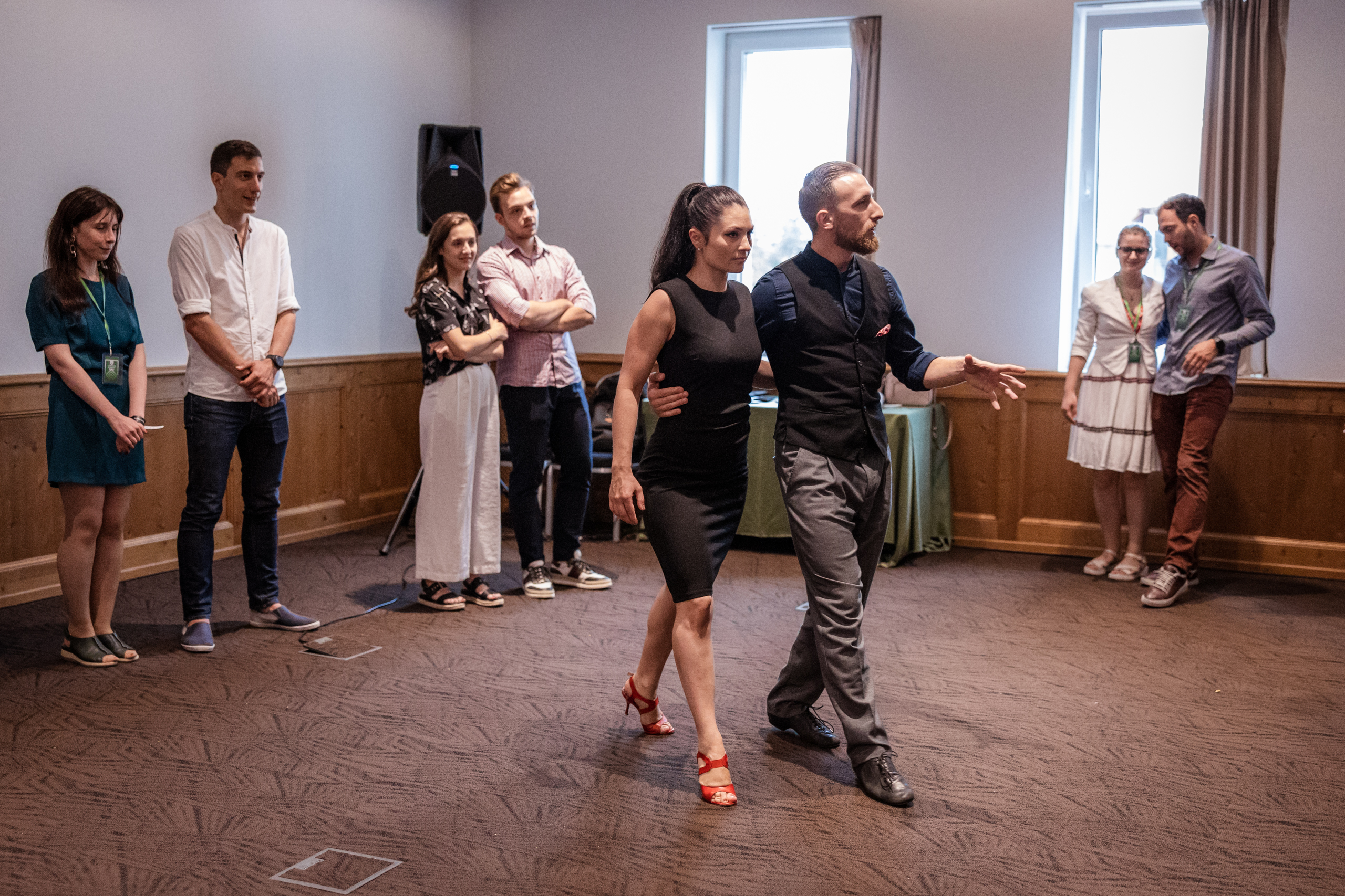 Un cuplu de instructori de tango inconjurati de cupluri ce participa la o lectie de grup de tango argentinian